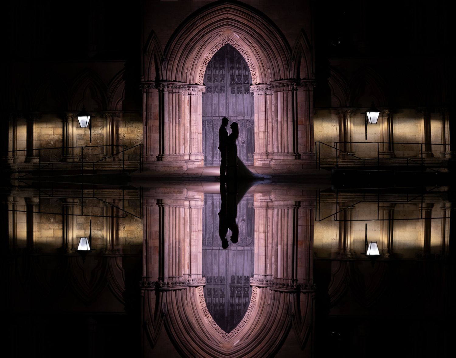 Dramatic silhouette against illuminated Gothic archway with perfect reflection in water.