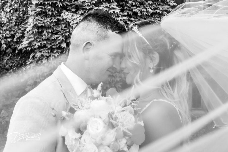 Elegant white wedding dress details with delicate lace and flowing fabric in natural light.