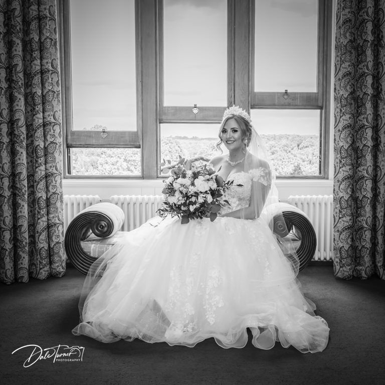 Elegant white wedding dress displayed across a window seat with natural light streaming in.