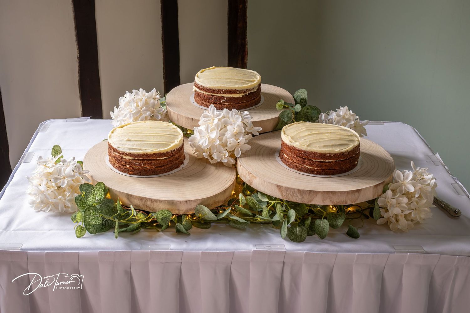 Wooden cake stands decorated with greenery for rustic wedding reception.