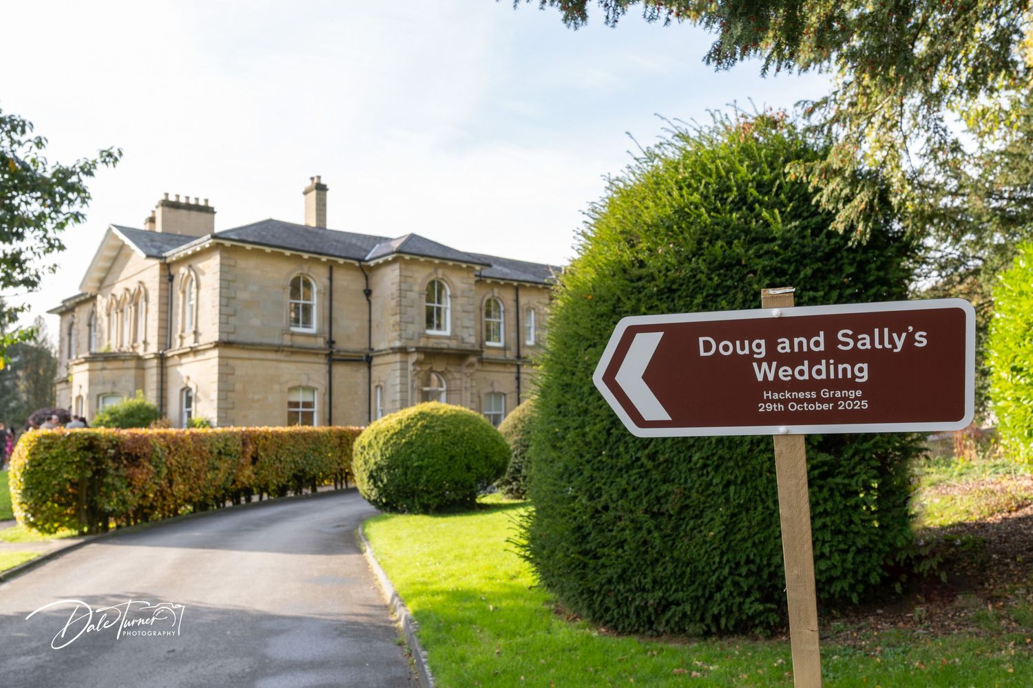 Panoramic view of a historic stone manor house with manicured grounds and gardens.