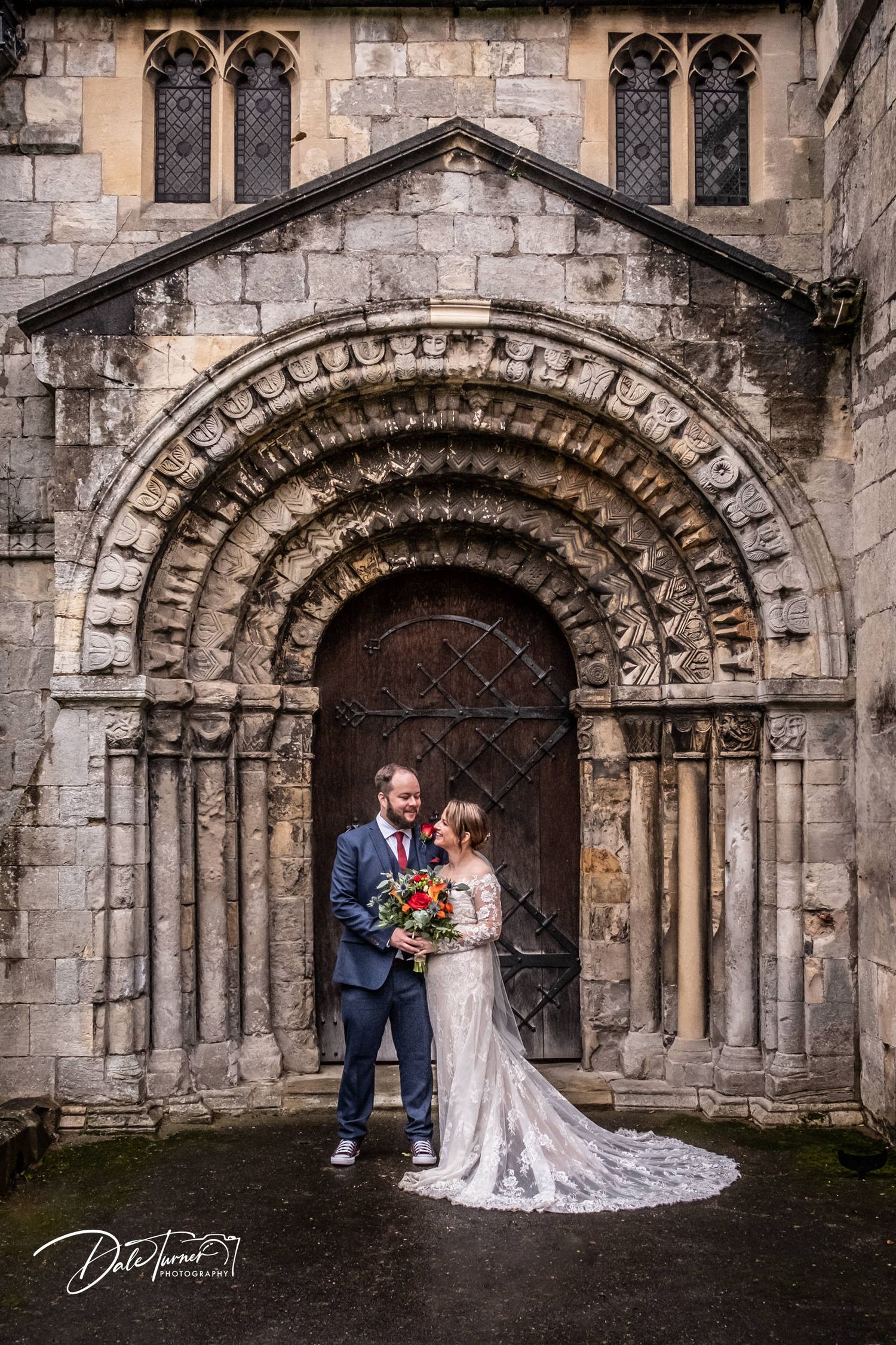 Romanesque stone archway entrance with intricate carved details and Gothic windows.
