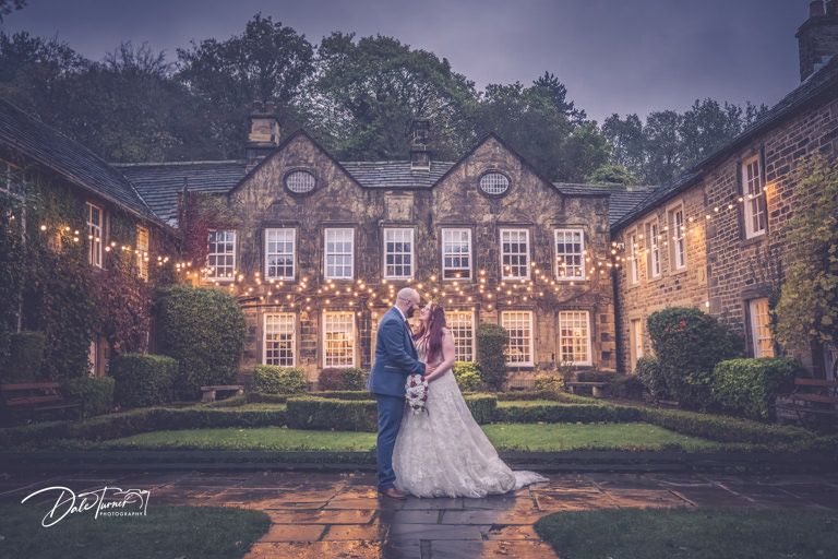 Evening wedding photos at illuminated stone mansion with dramatic lighting.