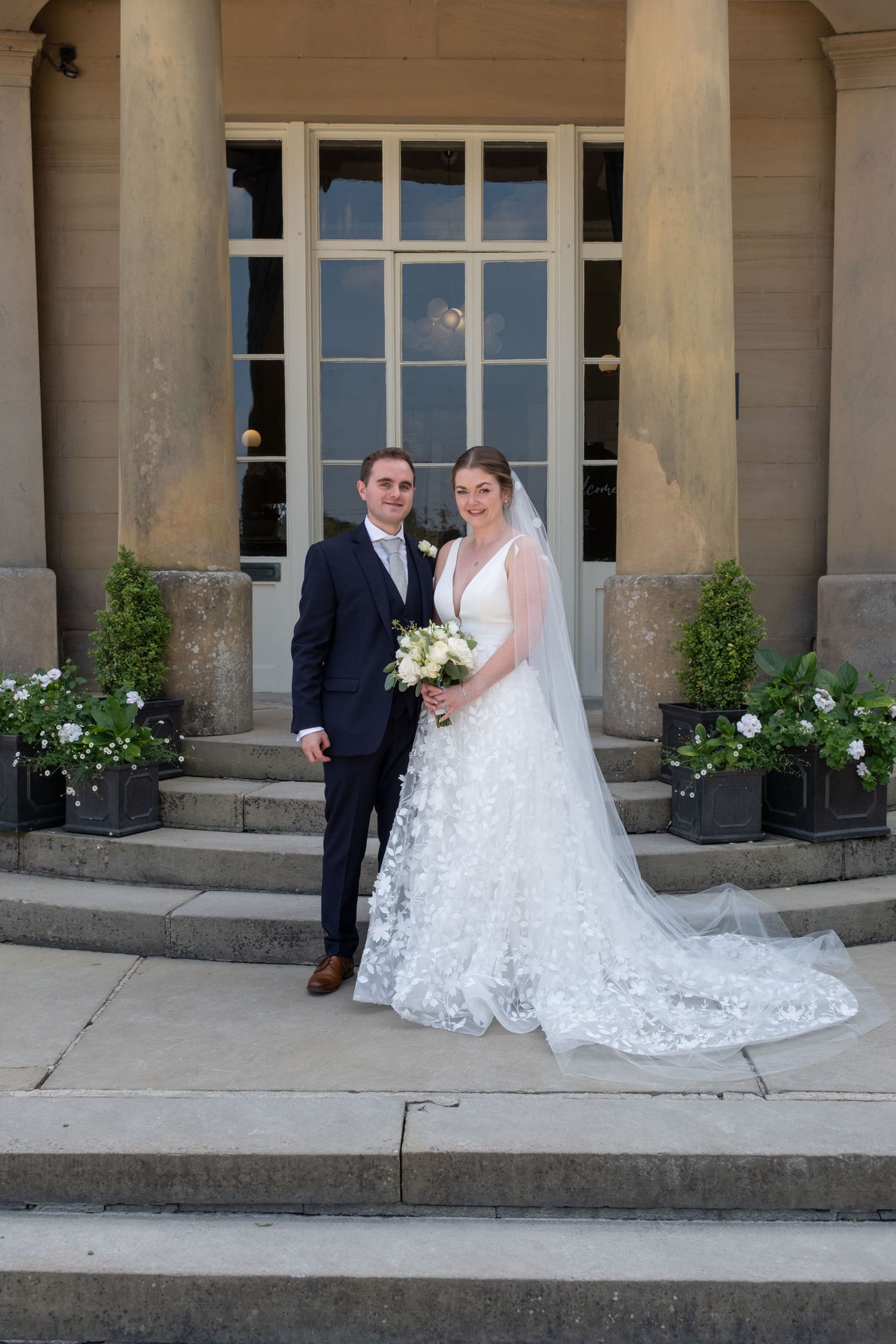 Wedding photography on the steps of an elegant stone building with classical columns.