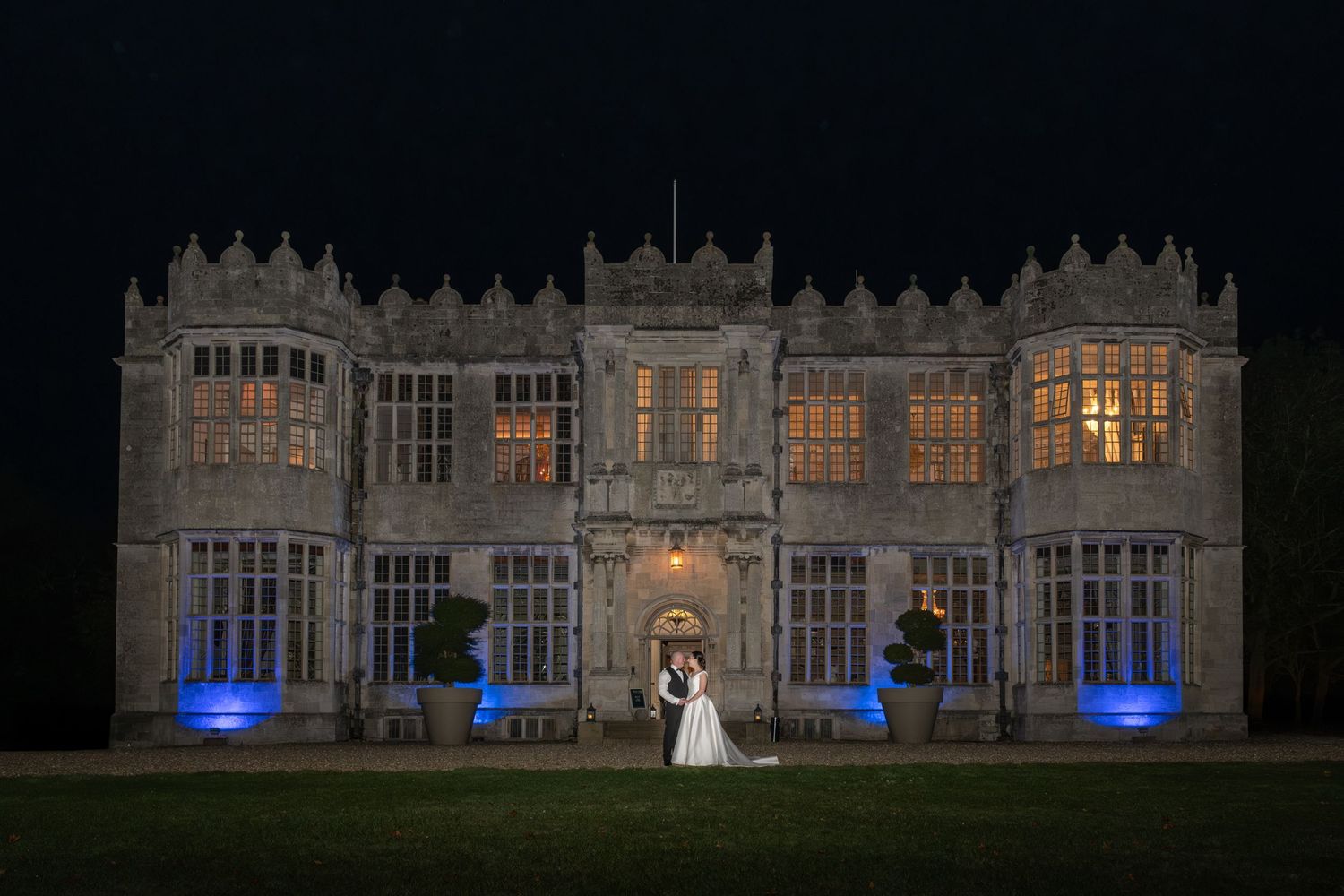 Historic mansion facade lit dramatically at night with blue uplighting.