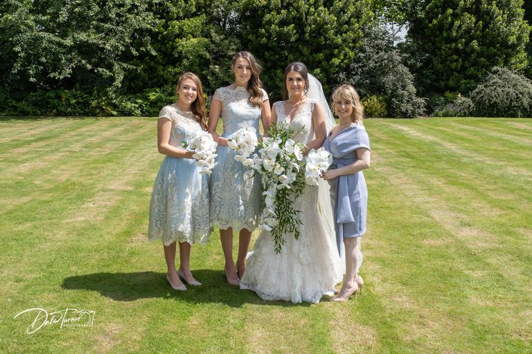 Wedding party gathers on manicured lawn for formal photographs.