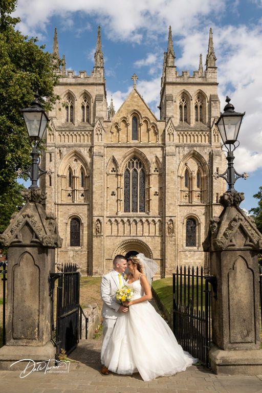 Gothic cathedral exterior with ornate stone architecture and spires against blue sky.