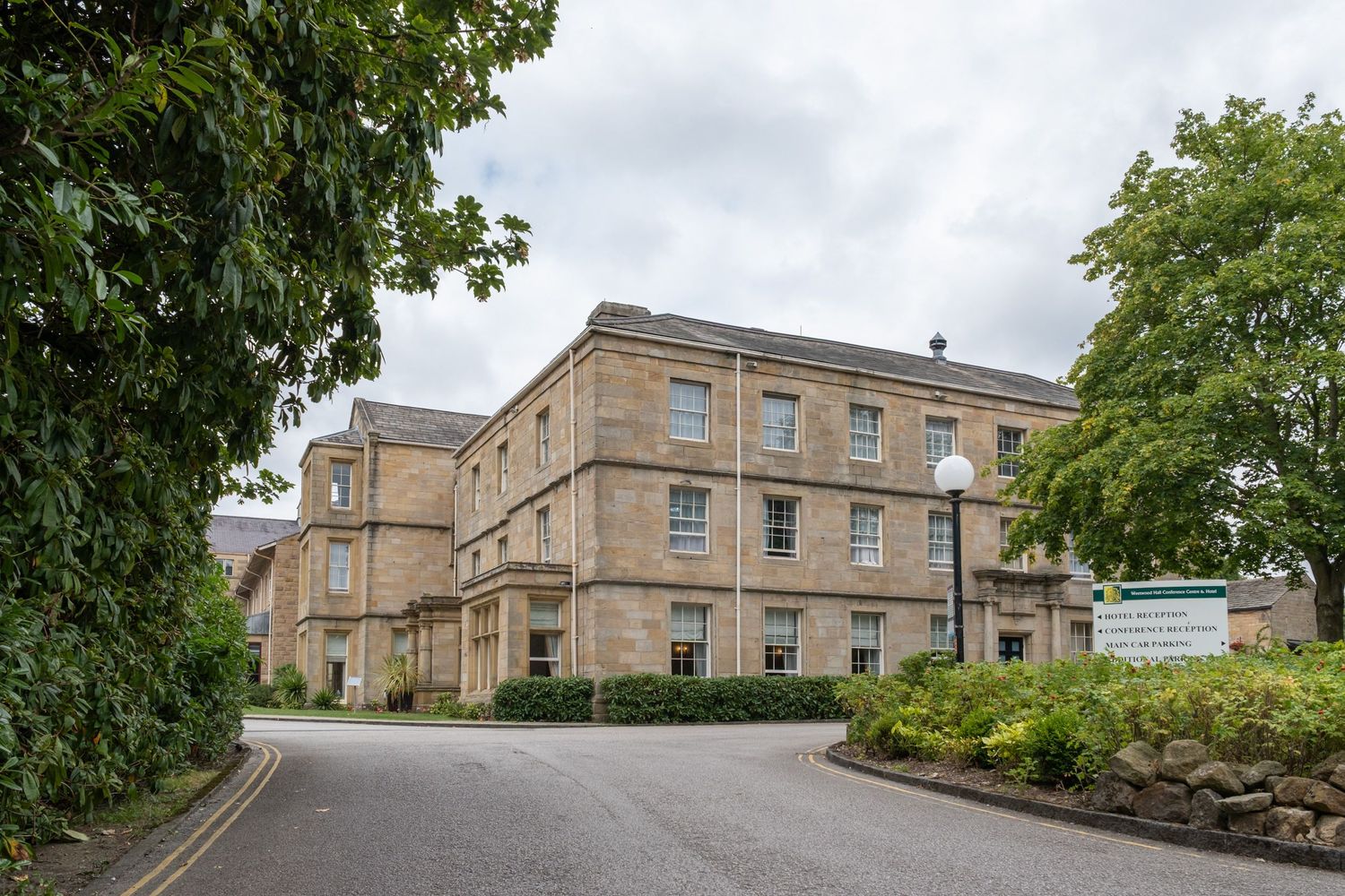Stone building exterior with classic architecture and trees visible against an overcast sky.