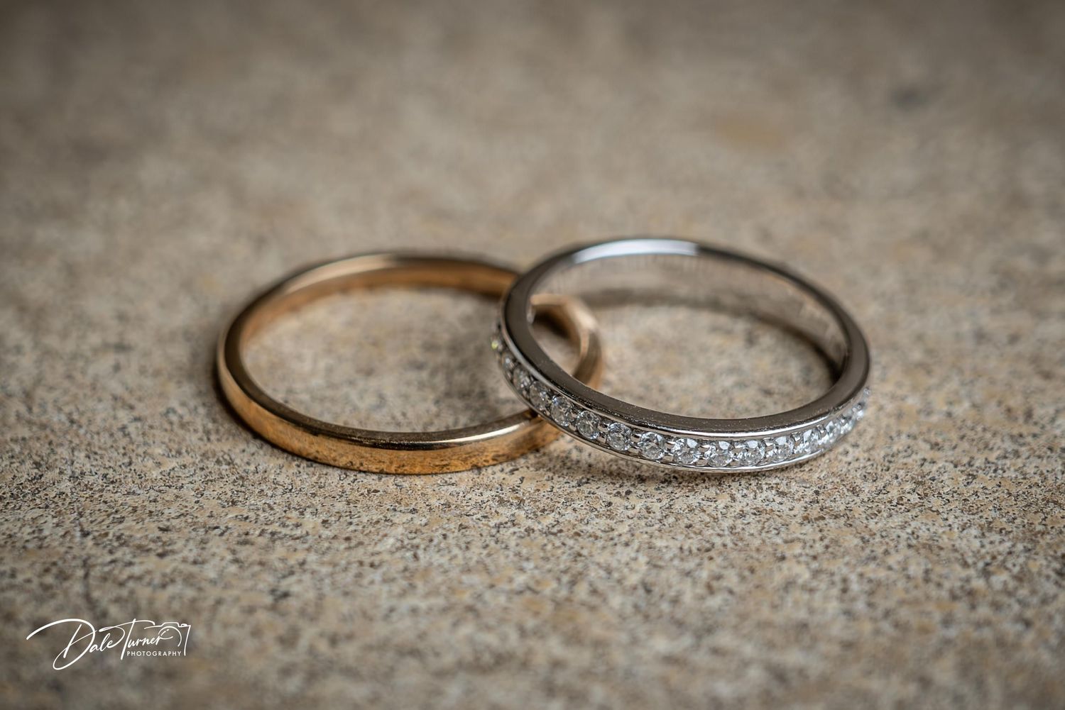 Close-up details of wedding rings on textured gray surface.