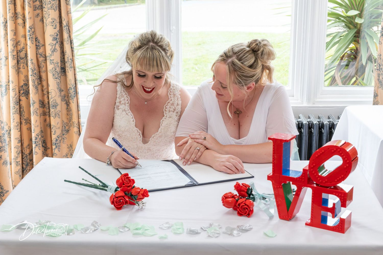 Red LOVE letters decorate table at wedding reception with floral accents.