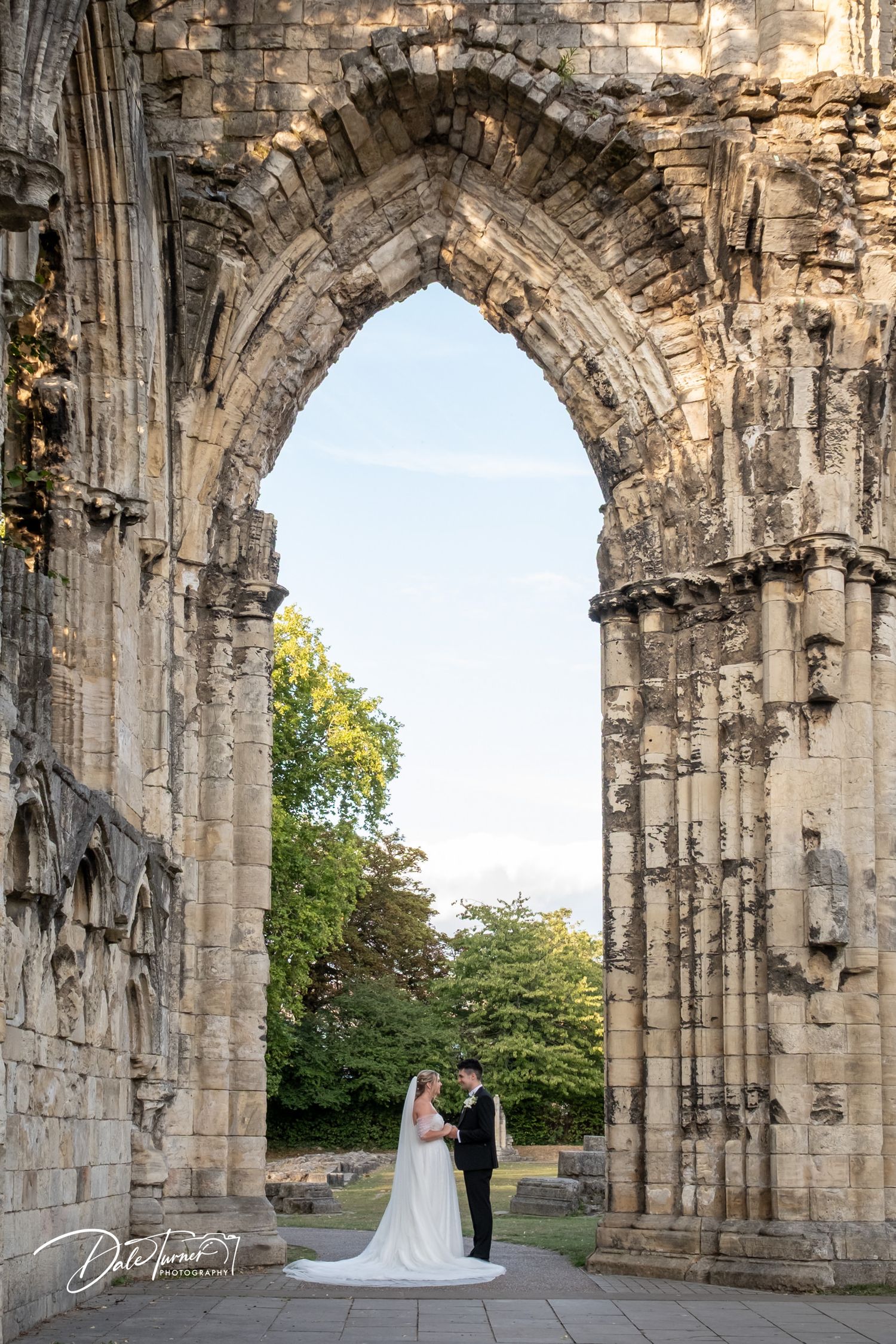 Wedding couple framed by dramatic stone archways of historic architecture.