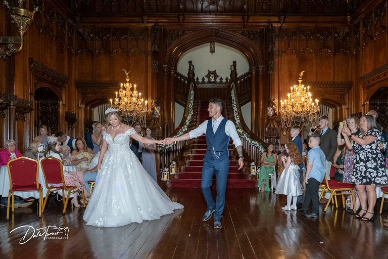Elegant wedding reception in a grand ballroom with ornate chandeliers and classic decor.