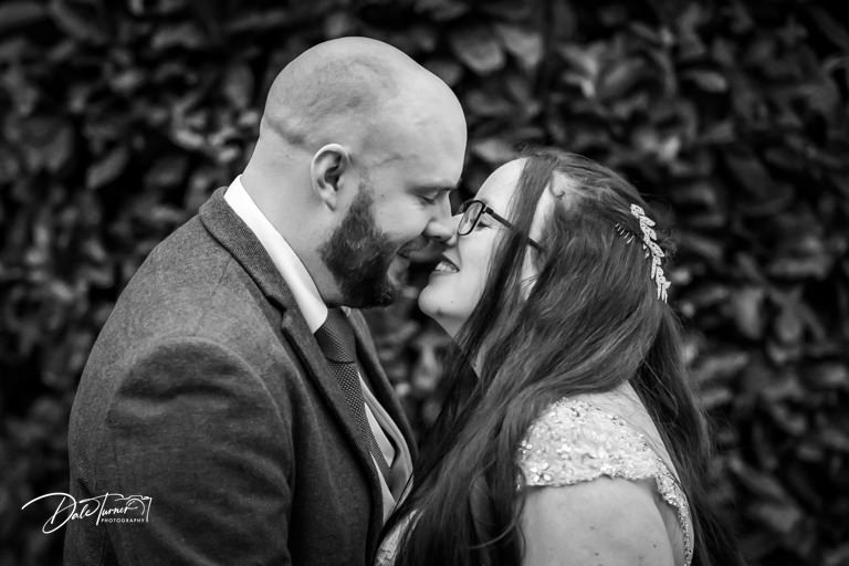 Intimate black and white wedding portraits against natural foliage backdrop.