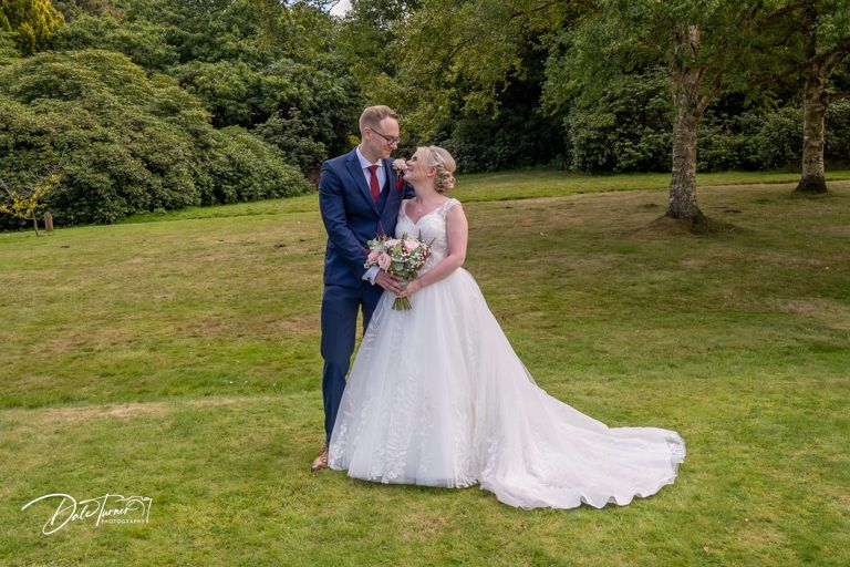 Wedding celebration on lush green lawn surrounded by mature trees and natural landscaping.