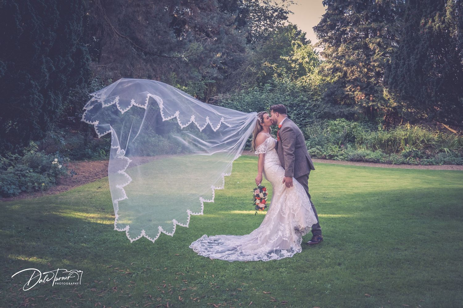 Ethereal outdoor wedding photography with flowing veil in natural sunlight.