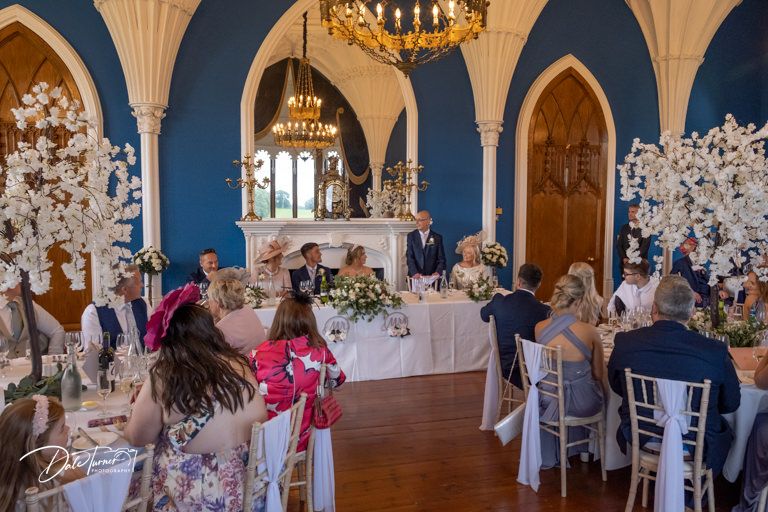 Grand ballroom with vaulted ceilings and blue walls decorated for a wedding reception.