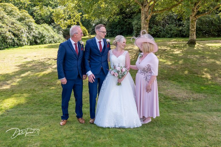 Wedding party of four poses together on sunny lawn during summer celebration.