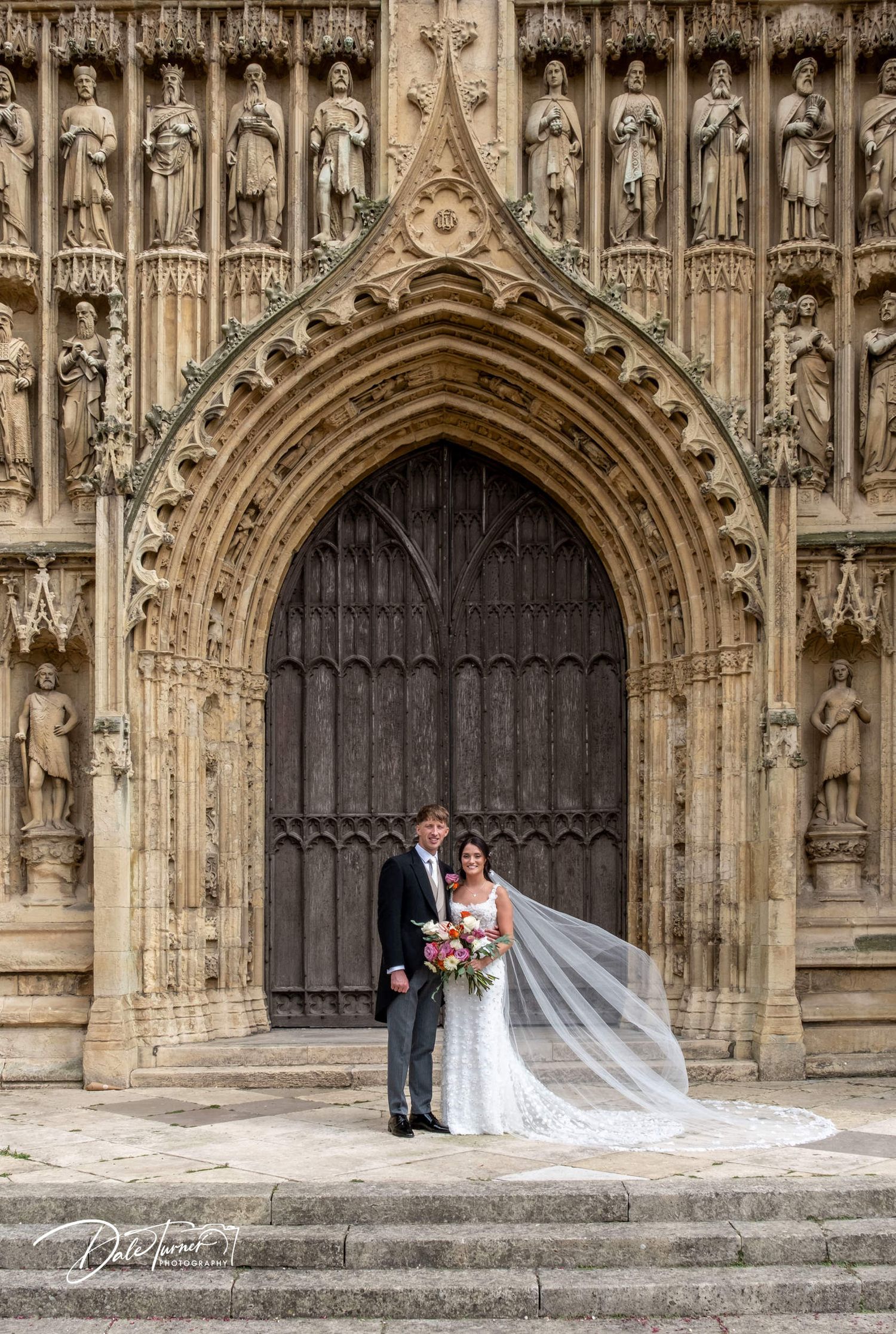 Stunning Gothic cathedral entrance serves as backdrop for wedding photography.