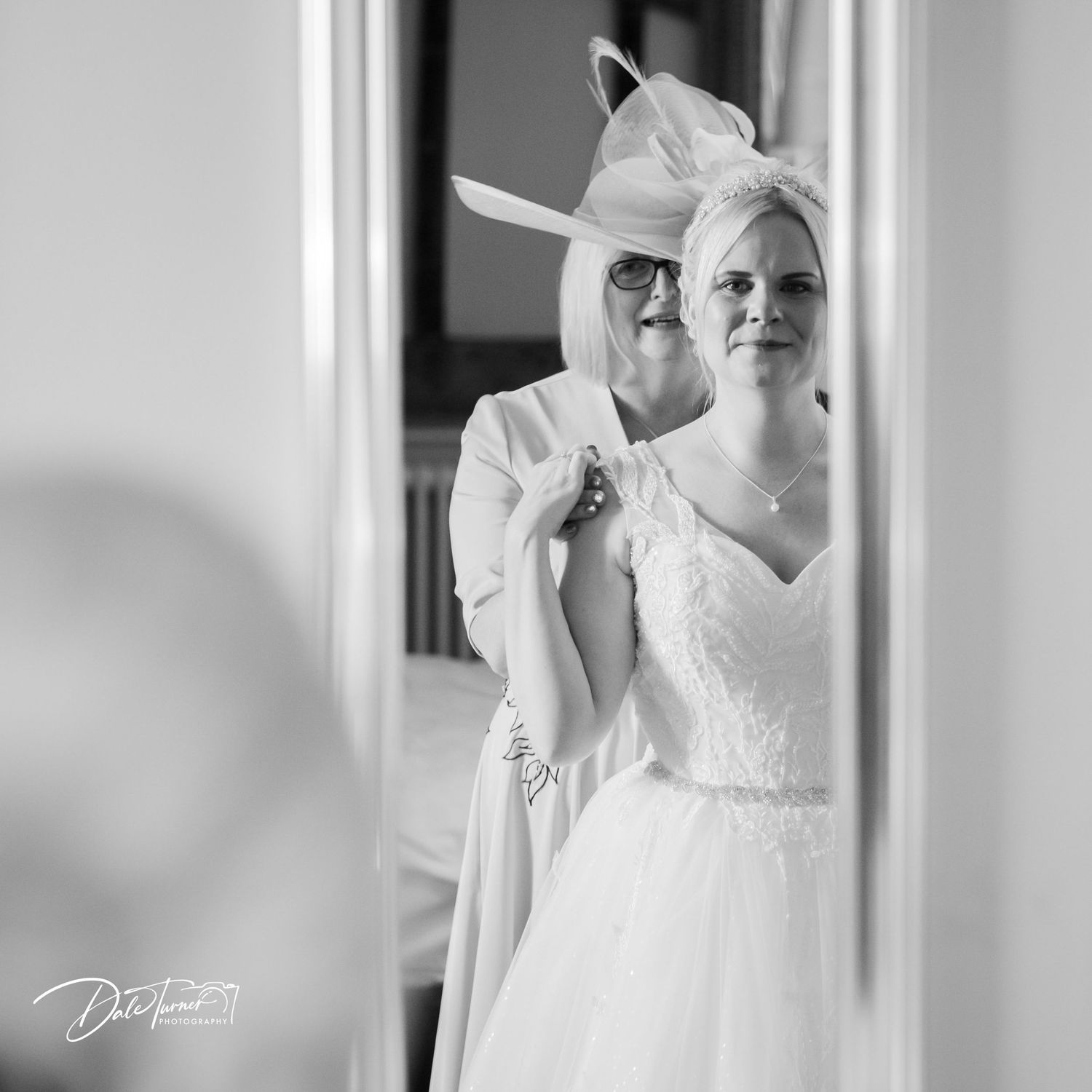 Elegant white wedding dress details shown in black and white photography with soft natural lighting.