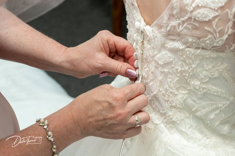 Close-up details of intricate lace and beading on white wedding dress.