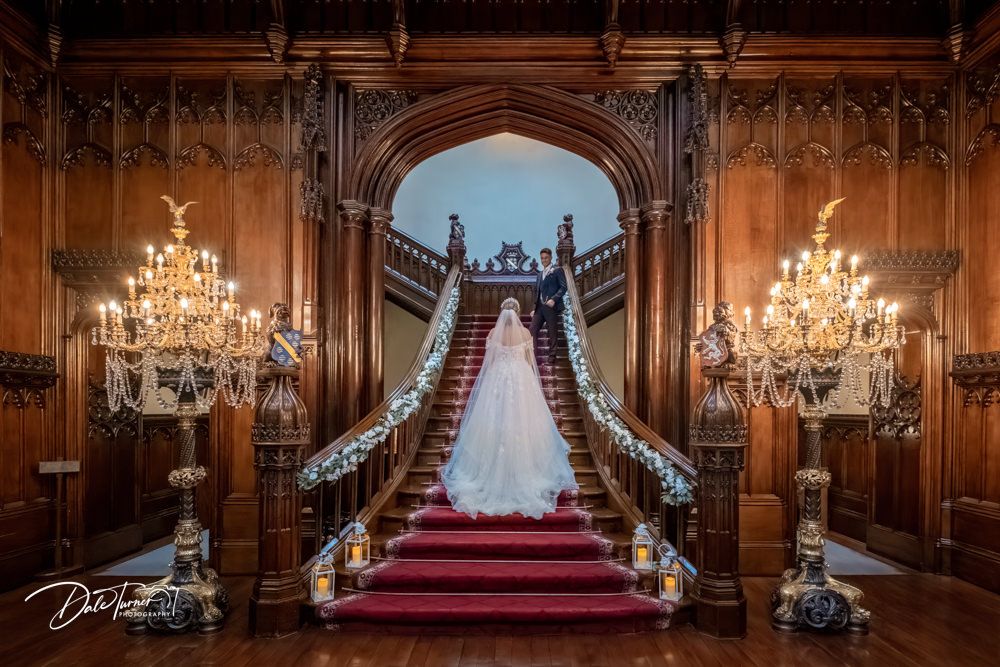 Gothic interior hallway with dramatic arches, red carpet runner and crystal chandeliers.