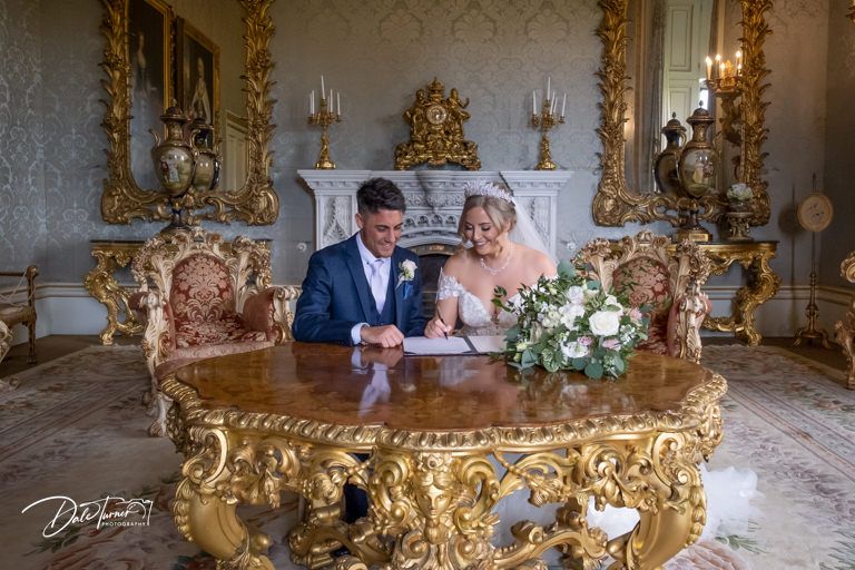 Ornate gold-framed mirrors line the walls of an elegant wedding venue.