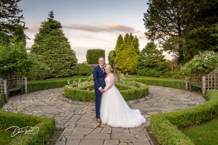 Stone pathway through manicured gardens creates romantic backdrop for wedding photos.