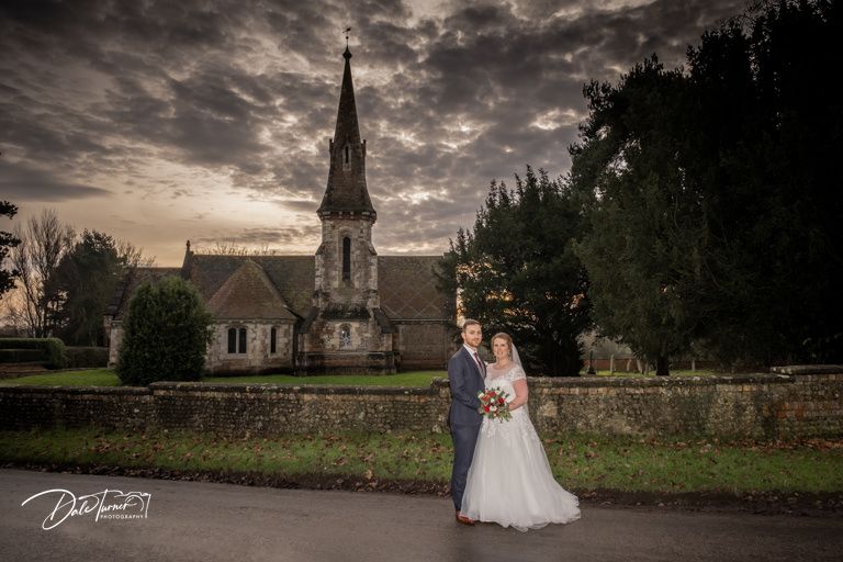 A dramatic wedding portrait with a historic stone church and moody sky in the background.