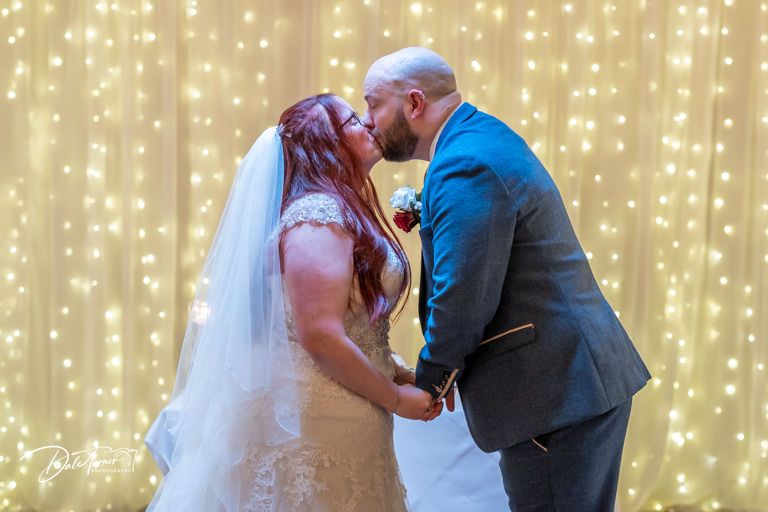Wedding couple sharing an intimate moment in front of a twinkling light curtain.