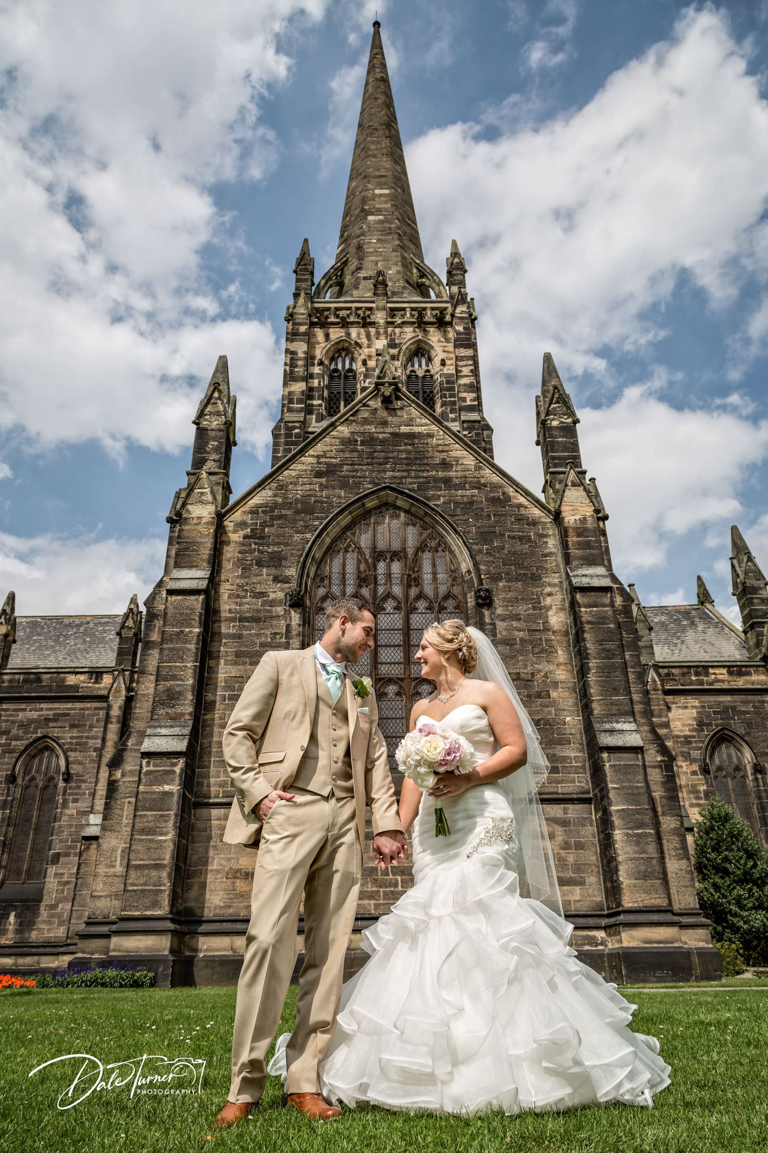 Gothic church spires rise against blue sky on castle grounds during summer celebration.