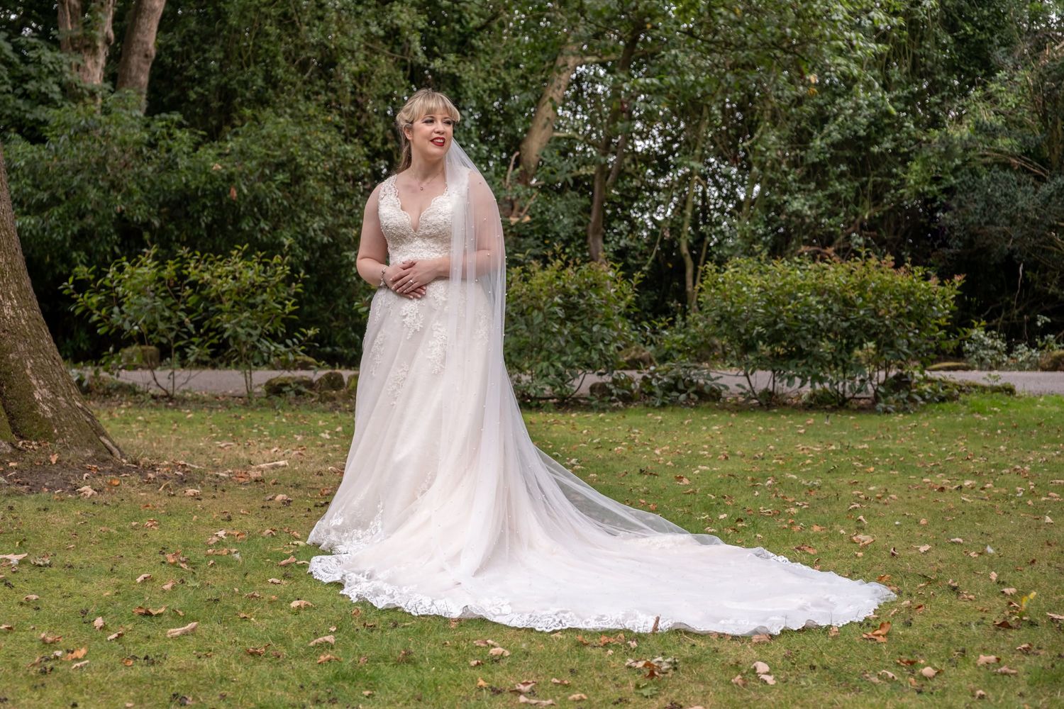 Outdoor wedding photography session in a garden setting with flowing white dress and train.