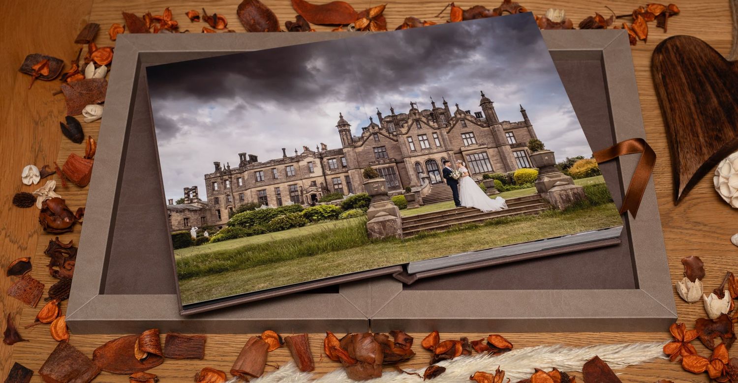 Wedding photo album display with autumn leaves and castle venue images.