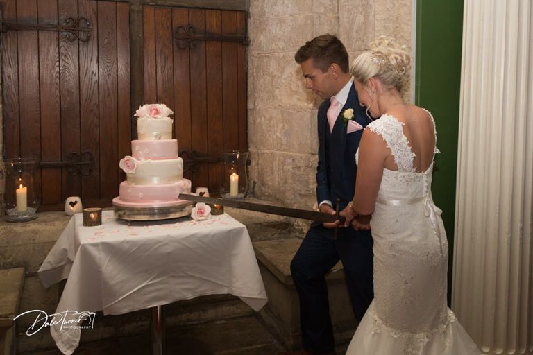 Wedding reception venue with elegant pink tiered cake and rustic wooden backdrop.