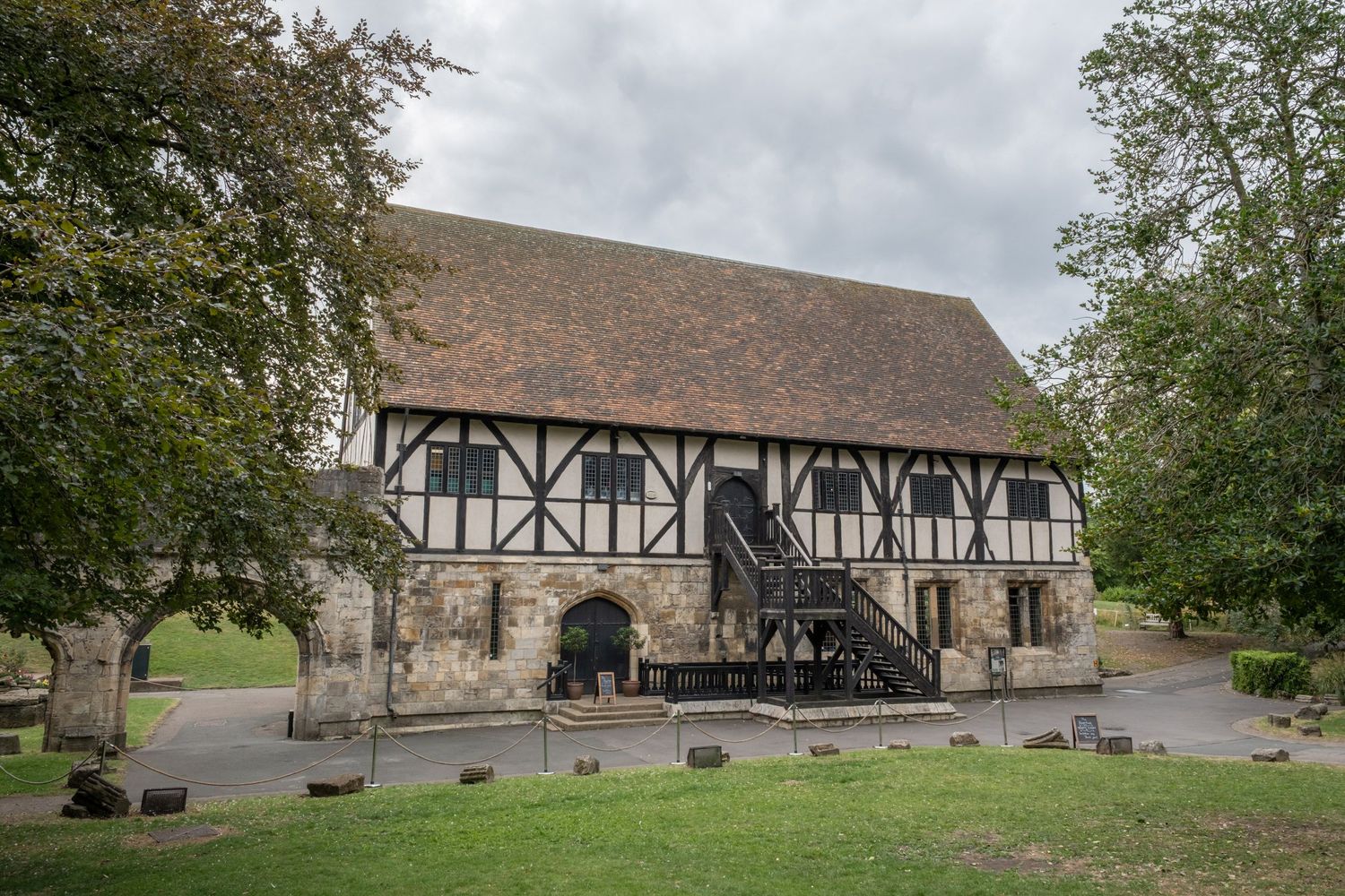 Tudor-style timber frame building with stone foundation in countryside setting.