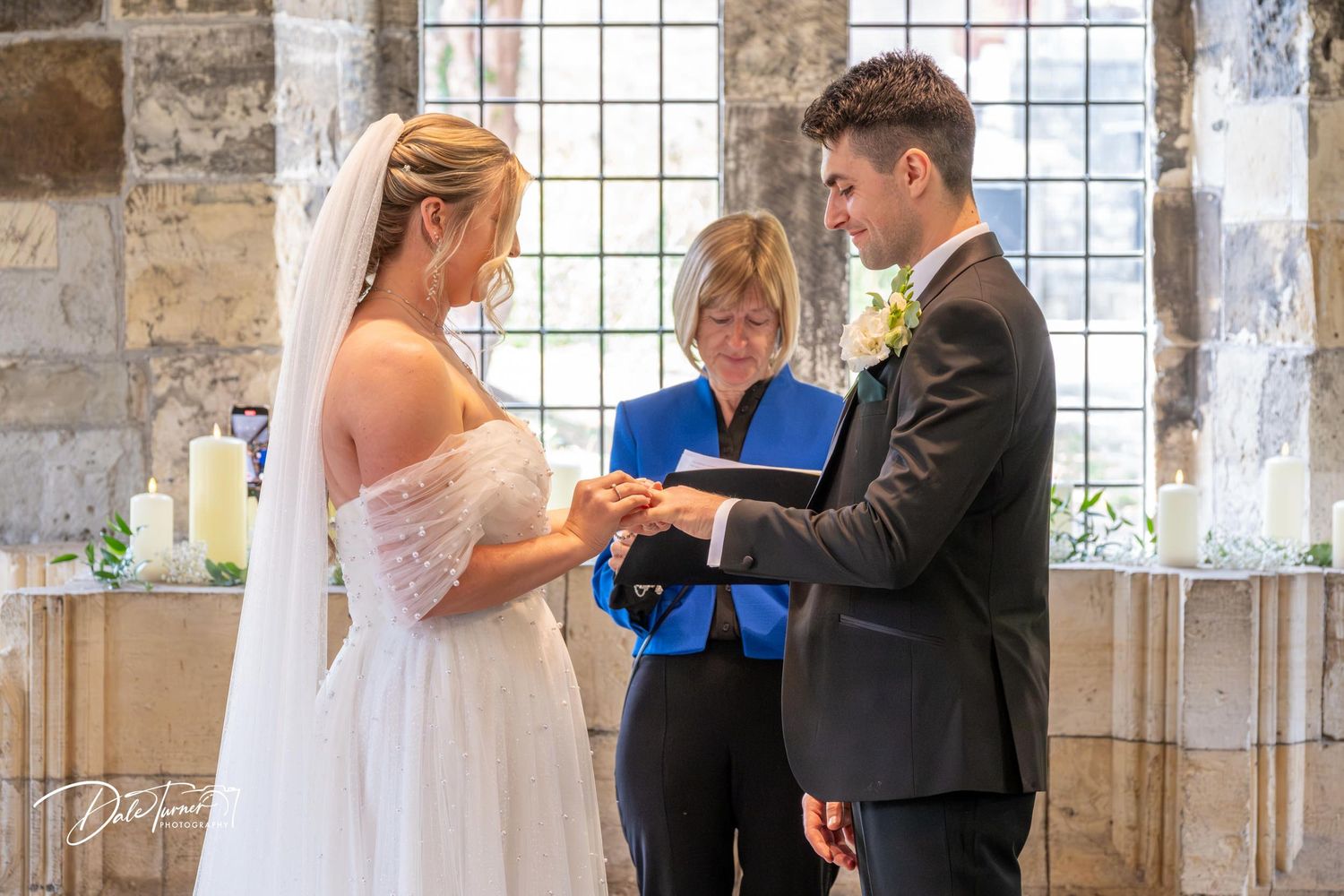 Wedding ceremony taking place in a historic stone church with large windows.