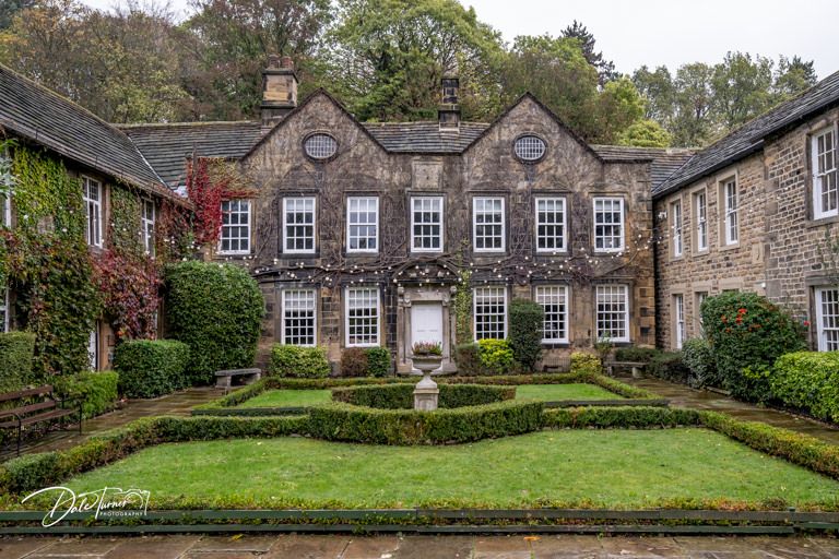 Panoramic view of historic stone mansion with manicured hedges and symmetrical windows.