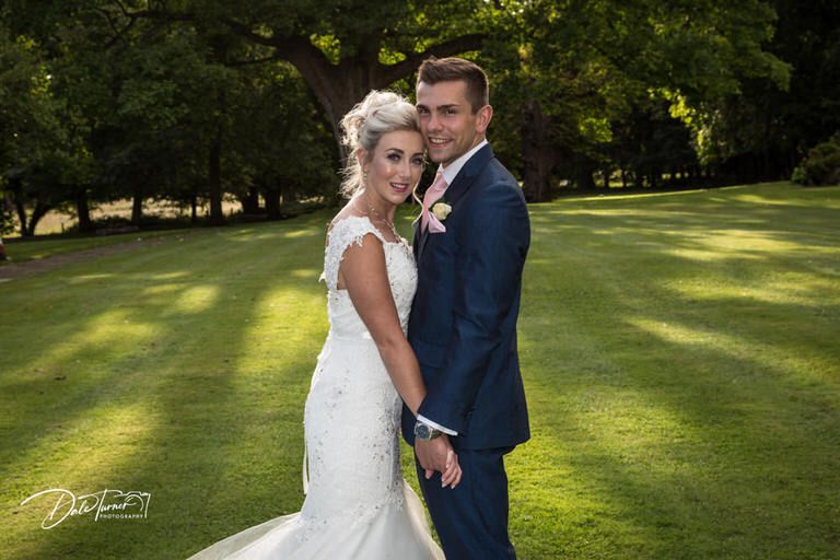 Newlywed couple shares romantic moments on a sunny golf course during their wedding photoshoot.