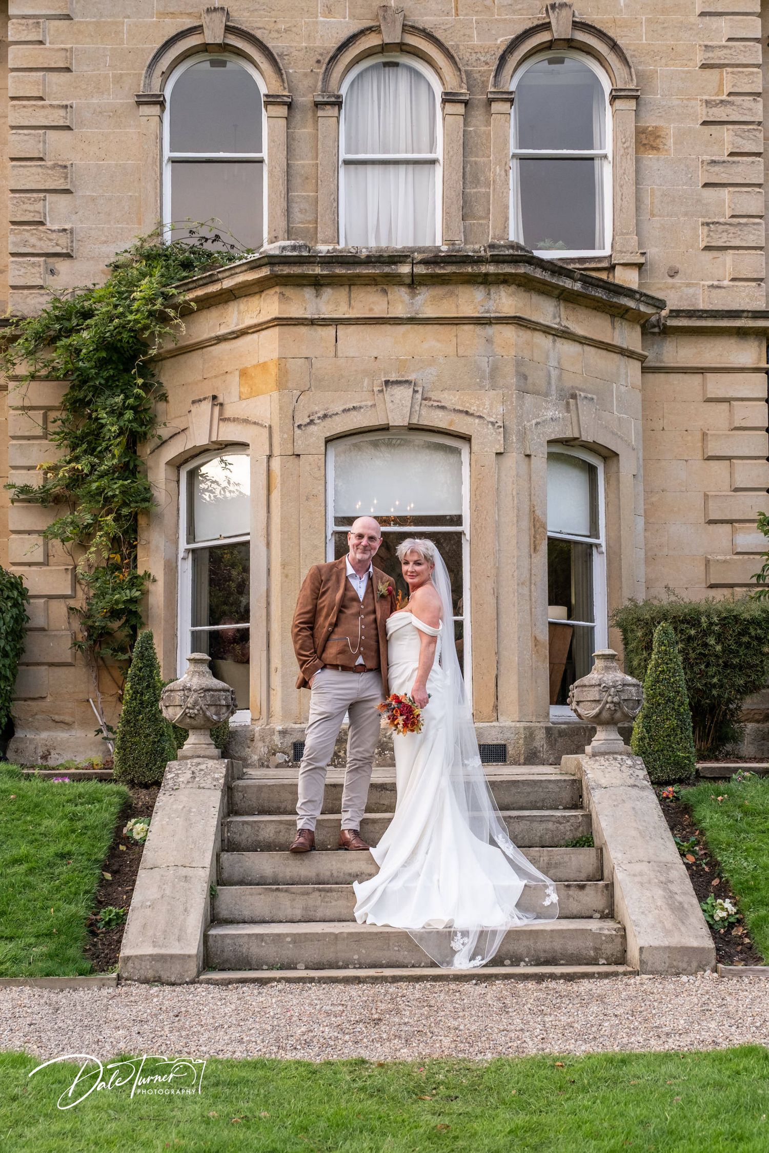 Elegant stone mansion entrance with steps and archways showcasing classic architectural details.