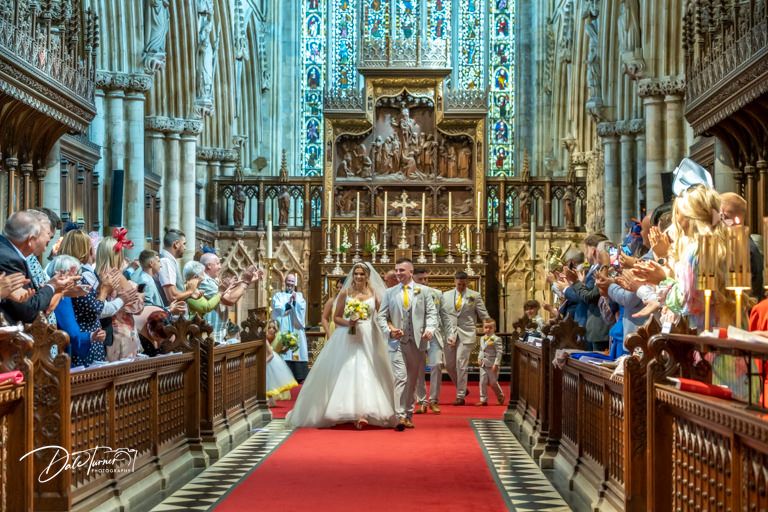 Cathedral nave with soaring gothic arches and red carpet leading to altar during wedding.