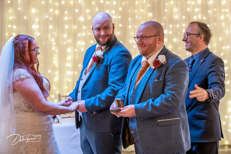 Wedding guests dance and celebrate under warm twinkle lights at an indoor reception.