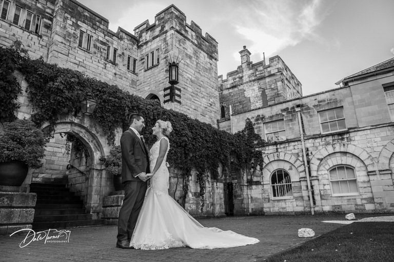 Black and white architectural photo of historic stone castle building with dramatic sky.