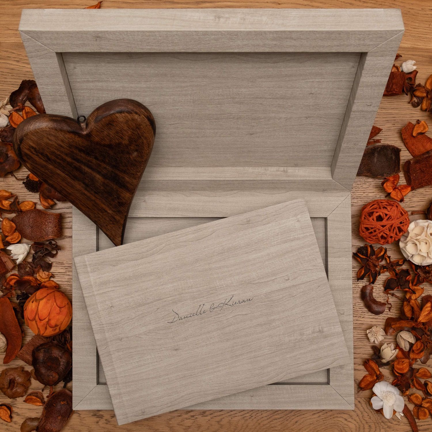 Elegant white wedding stationery and boxes arranged on wooden surface with autumn decor.
