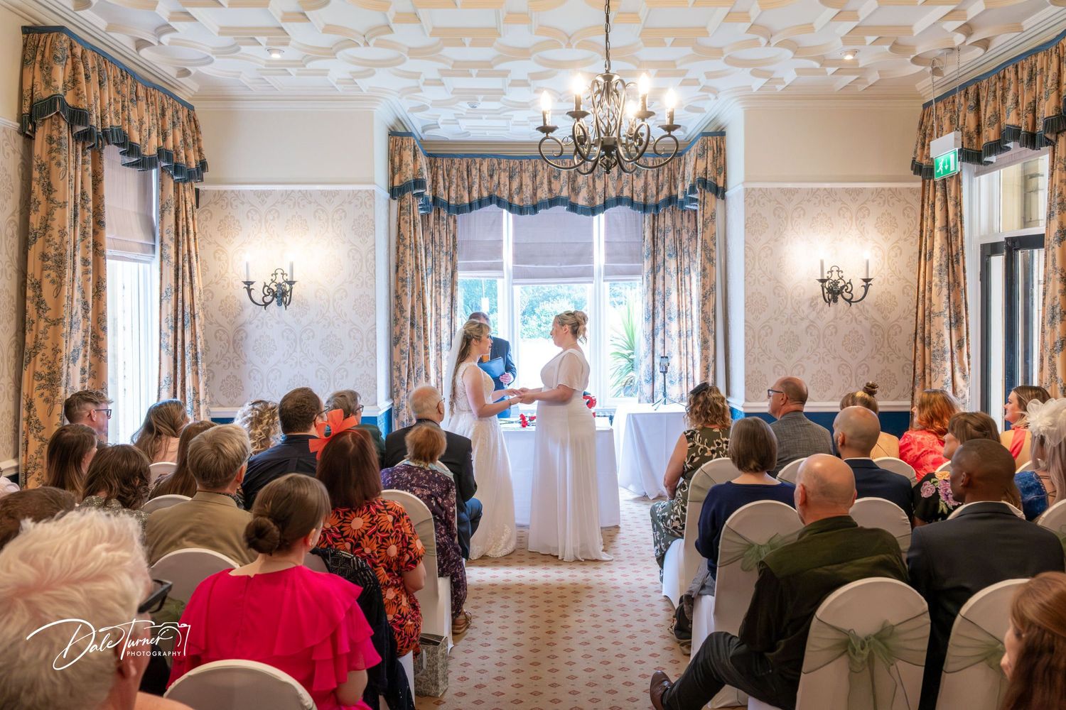 Wide shots of an elegant wedding venue with chandeliers and gathered guests.