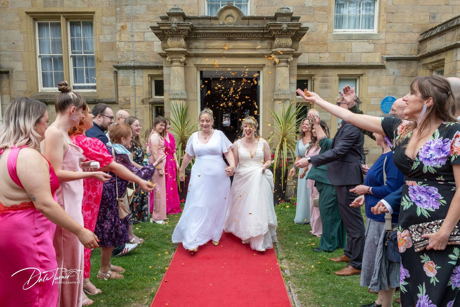 Wedding celebration outside historic stone building with guests forming reception line.