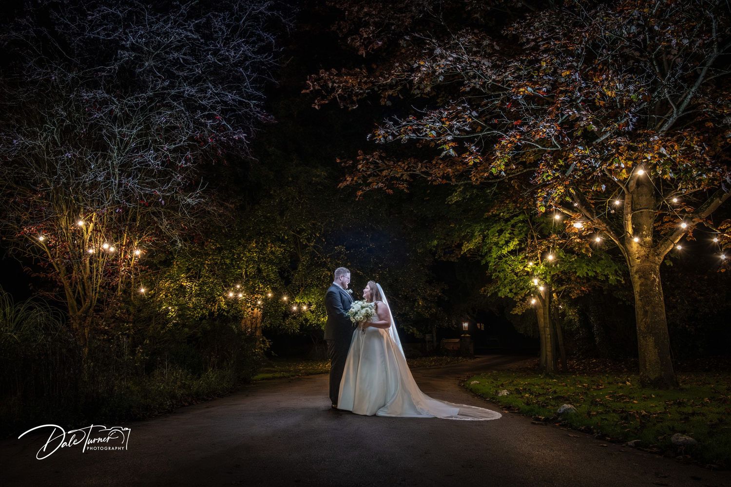 A romantic evening wedding scene in a garden with string lights illuminating the trees.