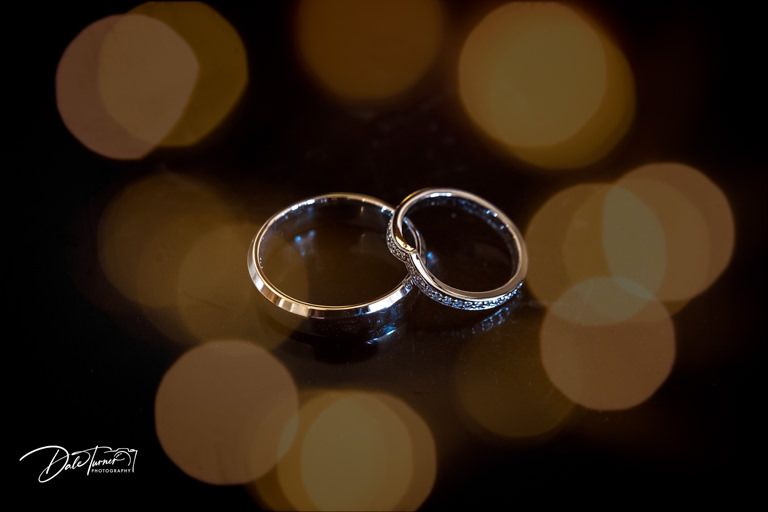 Wedding rings photographed with bokeh lighting effects in the background.