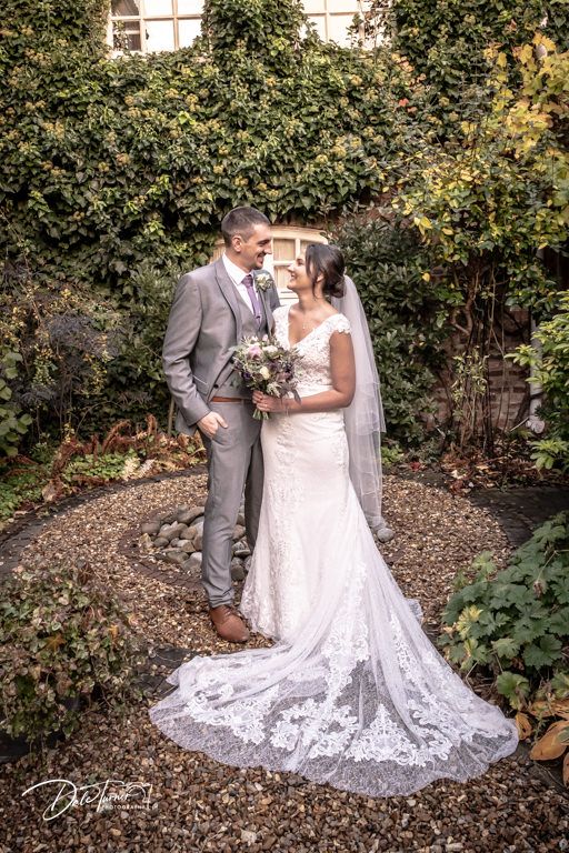 Wedding portraits in garden setting showing lace dress details against natural foliage.