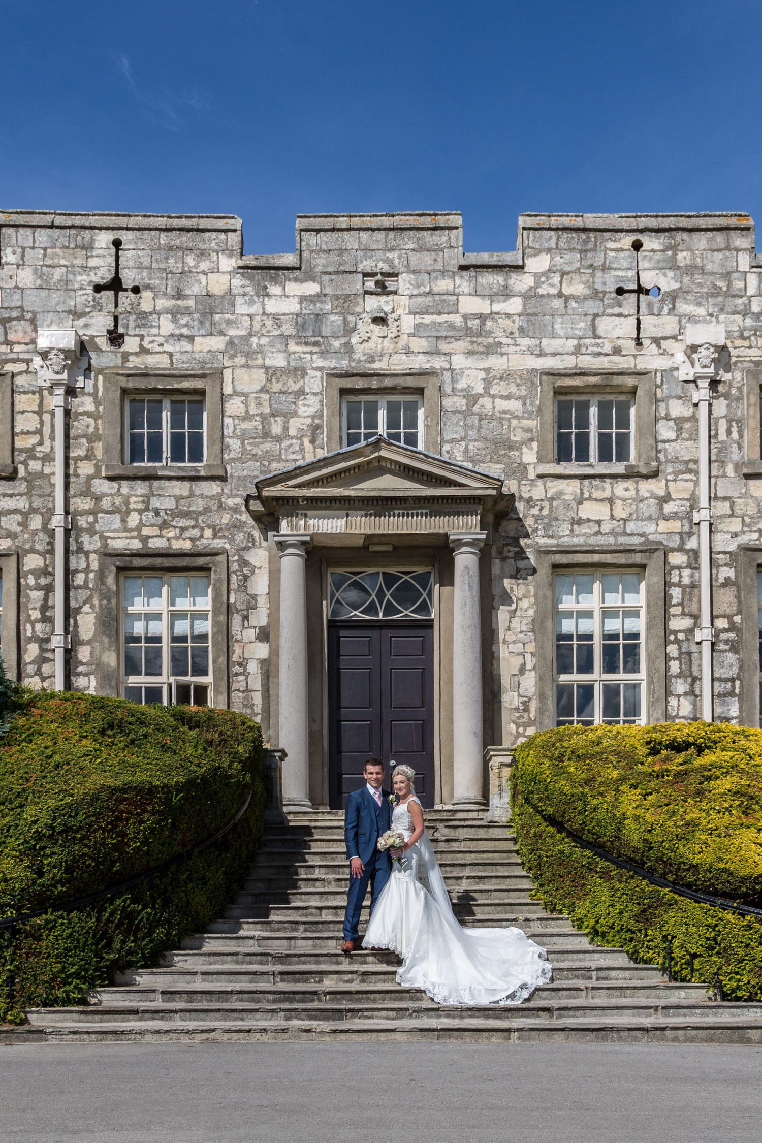 Wedding couple on grand stone steps of historic building with symmetrical architecture.