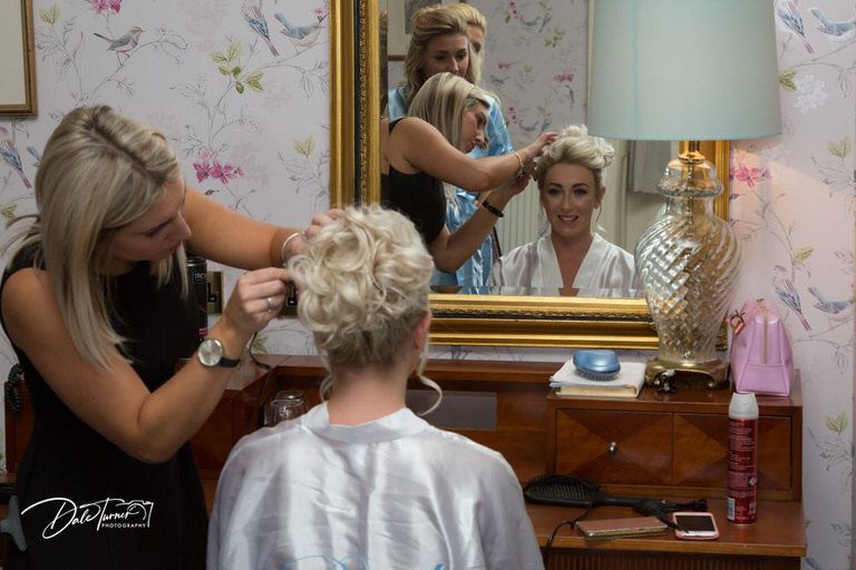 Getting ready scene with makeup and hair styling preparations before the wedding.