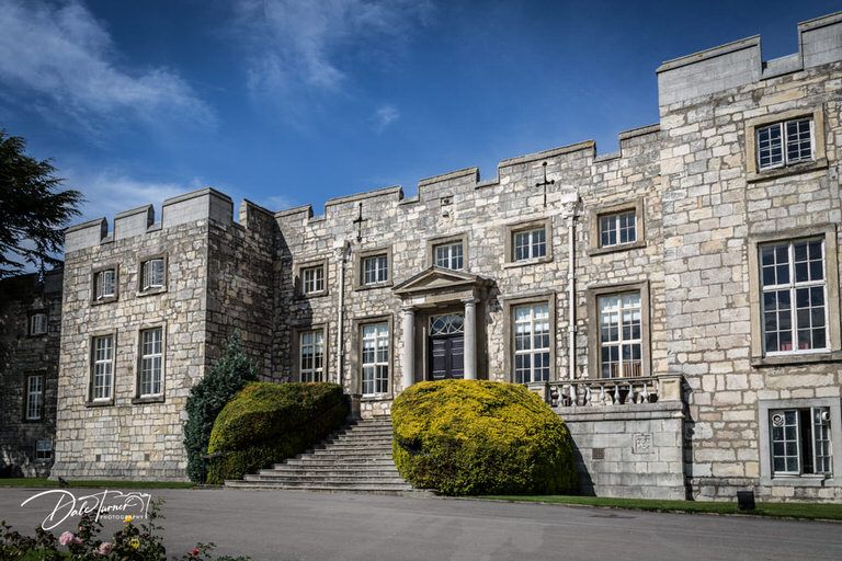 Stone castle facade with gothic windows and architectural details.